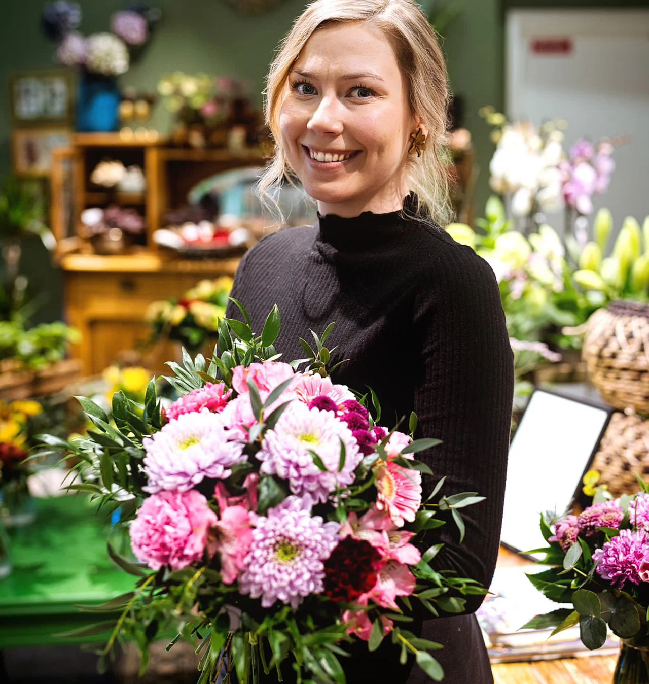 Sitomo floristti kukkakimpun kanssa myymälässä